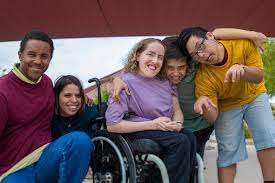 A diverse group of friends smiling together, one using a wheelchair