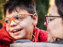 A boy in orange glasses laughing with his mother